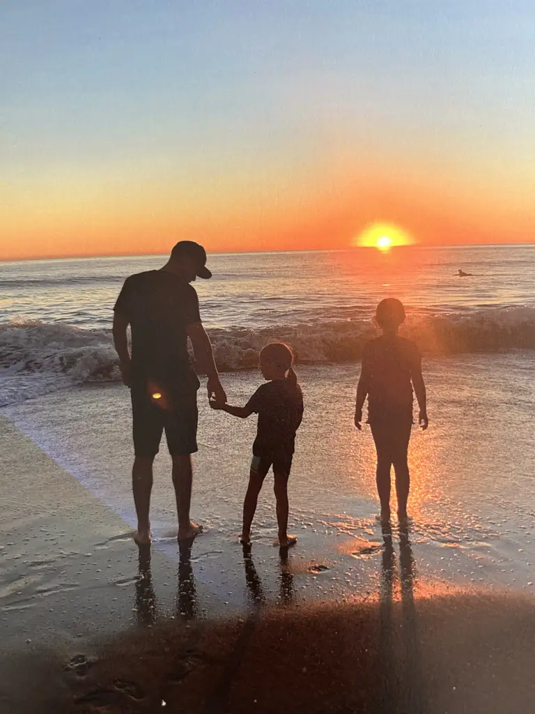 Brian and his daughters at the beach at sunset